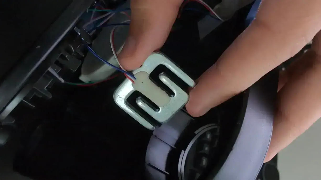 Close-up of a strain gauge sensor showing three cables: red, blue, and white